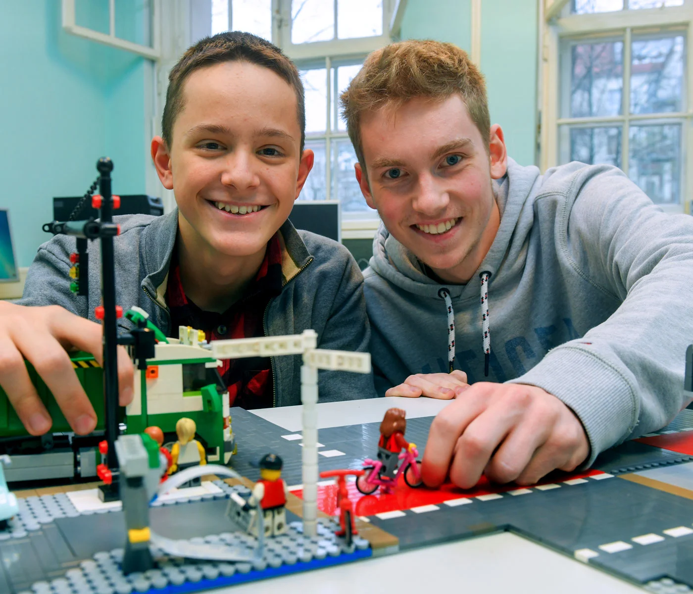 [Translate to English:] Angebote für SChüler: Zwei Jungen präsentieren lachend ihre Installation aus Lego.