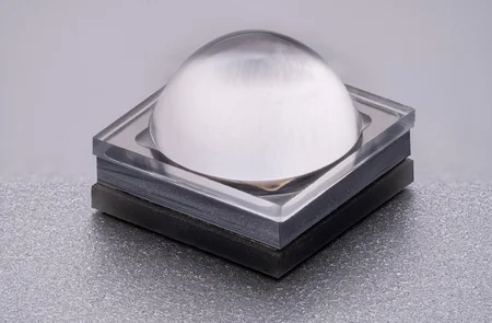 Close-up of a square LED with a transparent, dome-shaped lens.