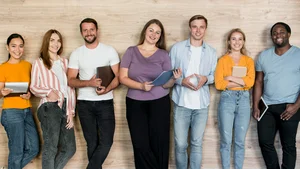 Gruppe von jungen, lächelnden Menschen vor einer Holzwand