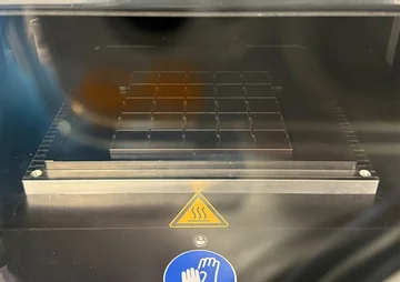 Metal plate with a grid for 25 samples behind a glass pane