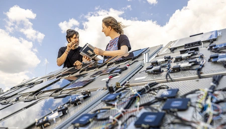 Zwei Personen an einer Anlage mit vielen kleinen Solarzellen
