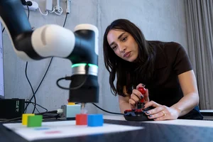 Junge Frau steuert ein Gerät zur Materialanalyse per Joystick