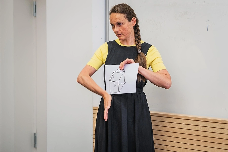 A woman shows a geometric drawing and explains it using her hands
