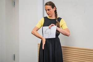 Frau zeigt eine geometrische Zeichnung und erklärt sie mit den Händen
