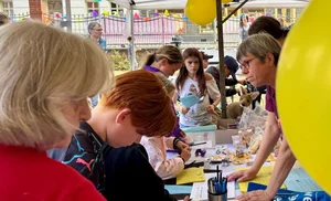 Kinder und Erwachsene an einem Stand mit Bastelmaterial und Luftballons