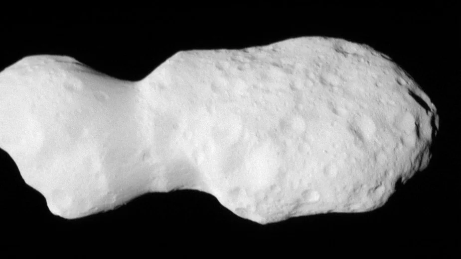 Nahaufnahme eines unregelmäßig geformten, kraterübersäten Asteroiden vor schwarzem Hintergrund