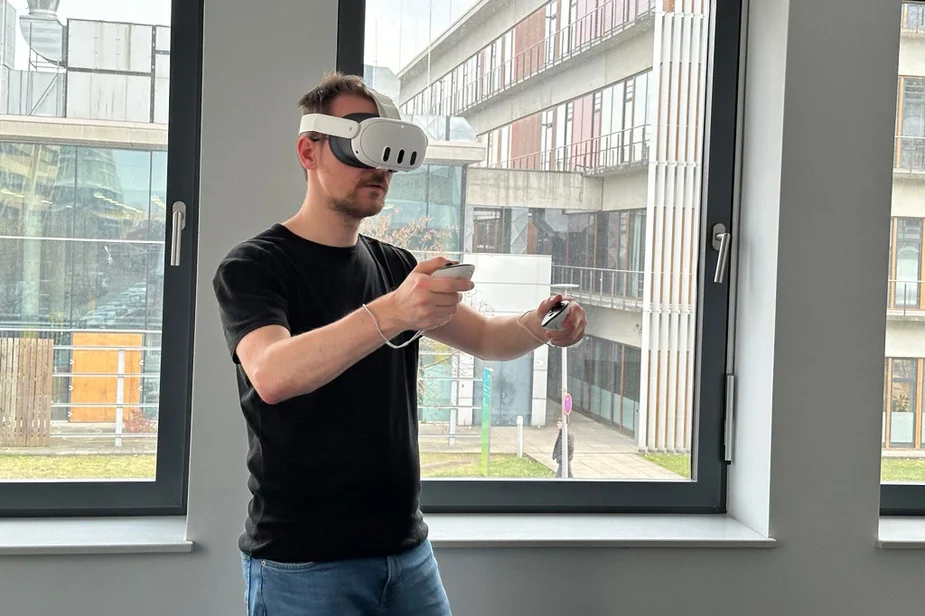 Mann mit einer VR-Brille auf dem Kopf und Steuerungsinstrumenten in den Händen
