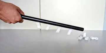 A hand holding a plastic stick with polystyrene flakes stuck to it