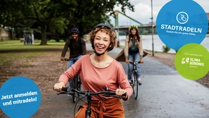 Drei Menschen mit Fahrrädern auf einem städtischen Radweg