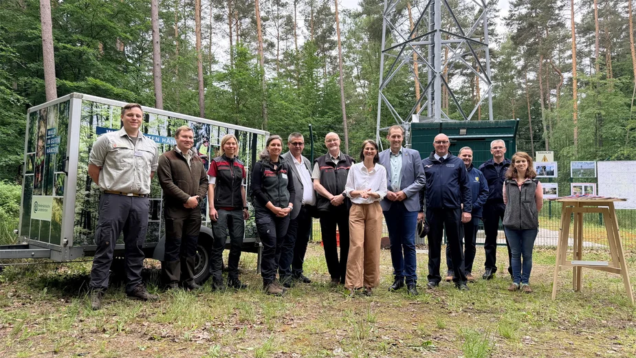 12 Personen vor einem Mast im Wald