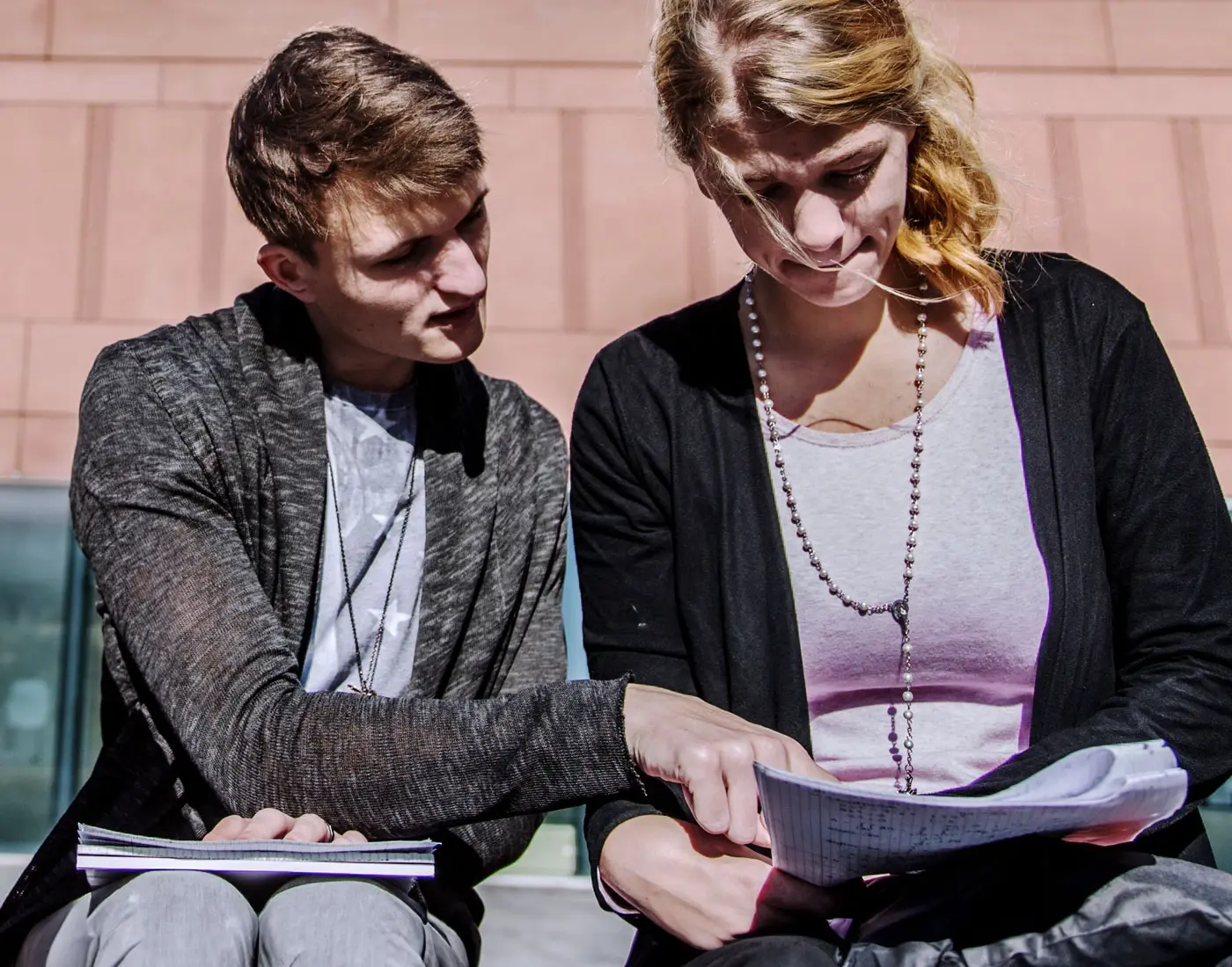 Students sit on a bench and go through their notes together.